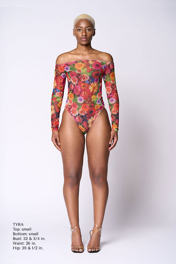 Model wearing a colorful floral off-shoulder bodysuit on a white background